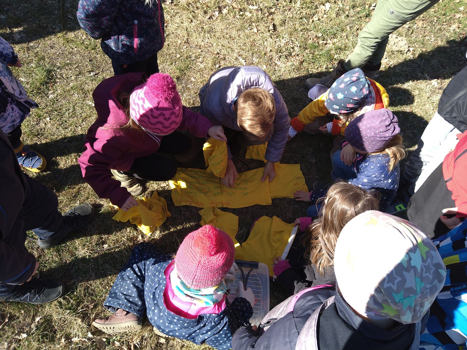 Mehrere Kinder legen Stoffe zusammen, auf denen ein Text steht.